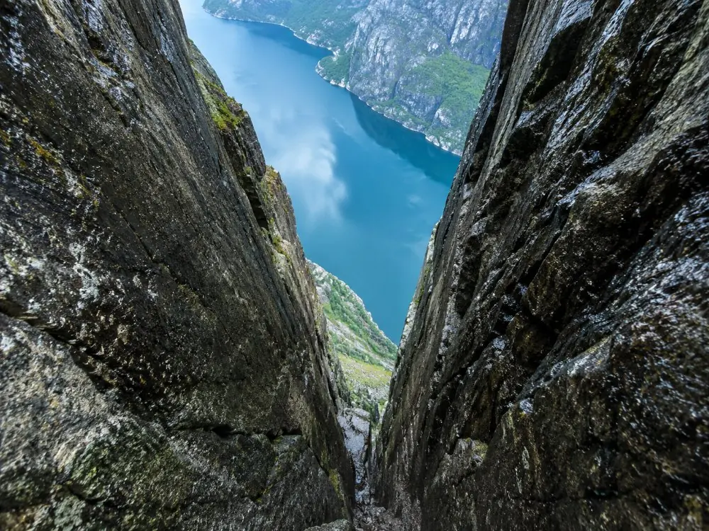 Kjeragbolten wedged between two rock walls, with the Lysefjord far below
